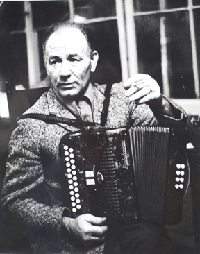 Joe Cooley sits with his accordion, a cigarette in one hand.